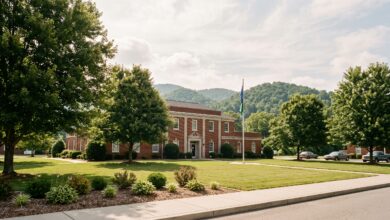 A brick municipal building with a flagpole behind a mown lawn and shade trees on a bright summer morning (illustrative)