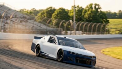 Stock car racing through a banked turn on a concrete superspeedway oval at golden hour, representing Nashville Superspeedway in Wilson County (illustrative)