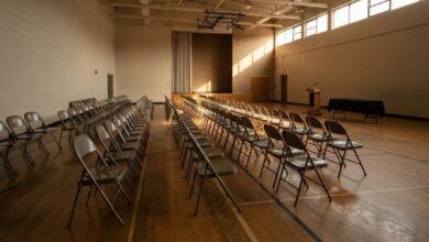 Rows of empty folding chairs set up in a school gymnasium before a public community meeting (illustrative)